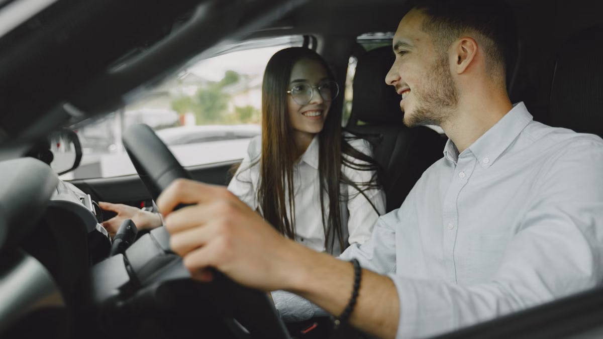 A smiling couple driving together in a car, enjoying their time on the road.